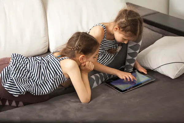 Hermanas con la tableta en el sofá en casa —  Fotos de Stock