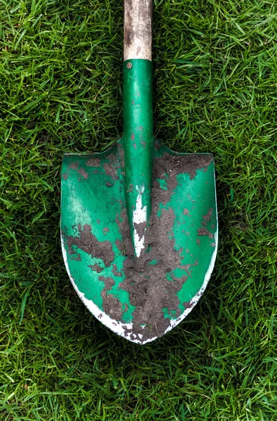Фото зеленой лопаты с почвой на траве — стоковое фото