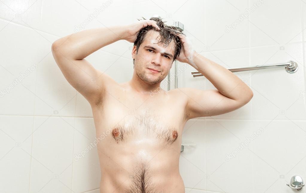 young man with muscular chest washing head at shower