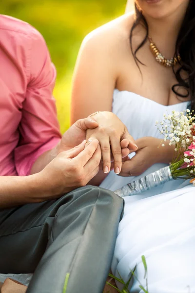 Novio poniendo anillo de oro en las novias mano en el parque — Foto de Stock