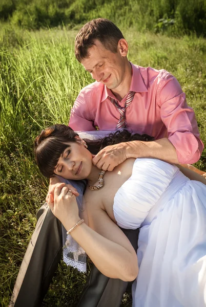 Portrait of beautiful bride lying on grooms knees at field — Stock Photo, Image