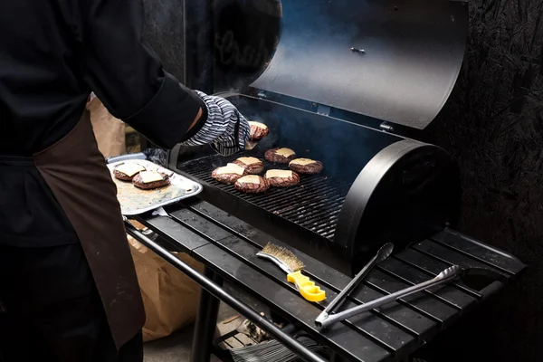 Photo of man cooking burgers on big grill — Stock Photo, Image