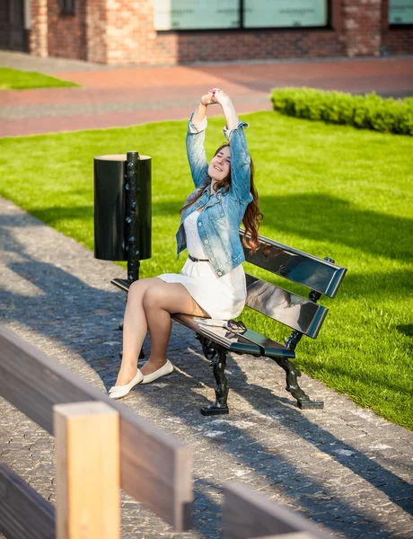 Foto de la mujer estirándose en el banco en el parque —  Fotos de Stock