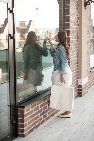 Mulher com saco de compras olhando para vitrines — Fotografia de Stock