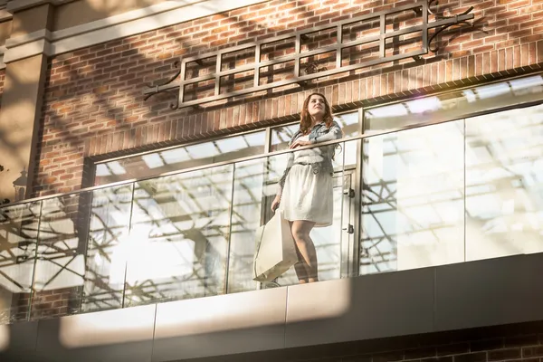 Young woman walking with shopping bag at terminal — Stock Photo, Image