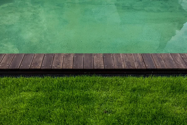 Riverbank with wooden path and green lawn — Stock Photo, Image