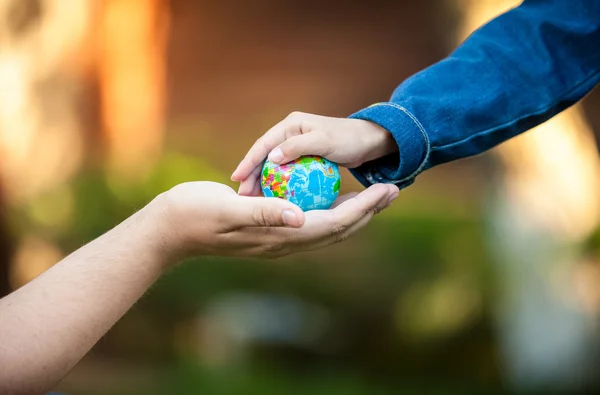 Männerhände und kleine Mädchenhände, die den Planeten Erde halten — Stockfoto