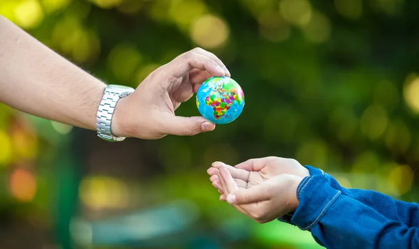 Man giving Earth globe to little girl — Stock Photo, Image