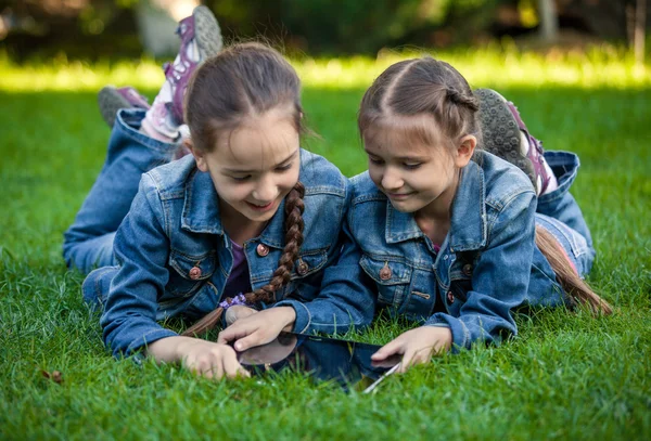 Two twin girls using tablet at park — Stock Photo, Image