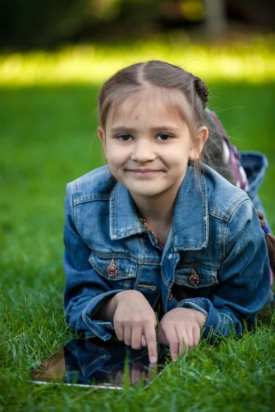 Malá dívka ukazuje na dotykový tablet na trávě — Stock fotografie