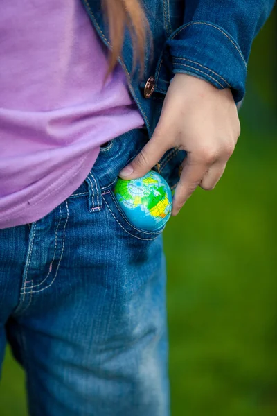 Концептуальное фото девушки, кладущей глобус в карман — стоковое фото