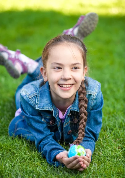 Девушка веселится на траве и держит глобус — стоковое фото