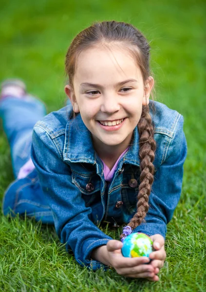 Девушка, держащая глобус в руках и лежащая в парке — стоковое фото