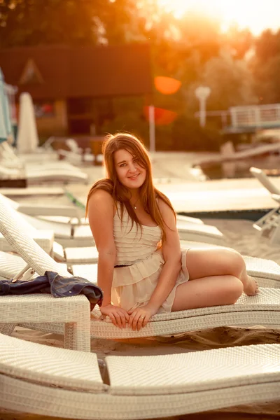 Женщина в платье расслабляется на пляже на закате — стоковое фото