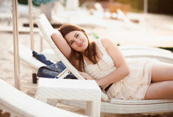 Vacker kvinna i klänning liggande på solarium på stranden — Stockfoto