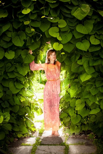 Donna romantica posa ad arco floreale in giardino — Foto Stock