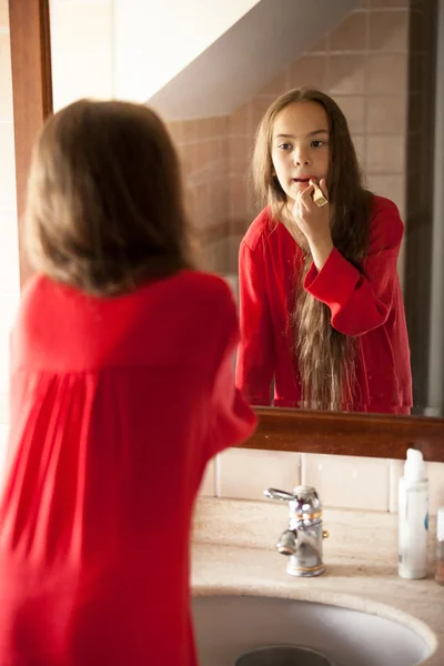 Portrait of little girl painting lips with red lipstick — Stock Photo, Image