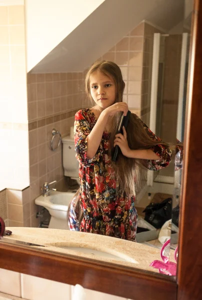 Little girl combing hair at bathroom — Stock Photo, Image