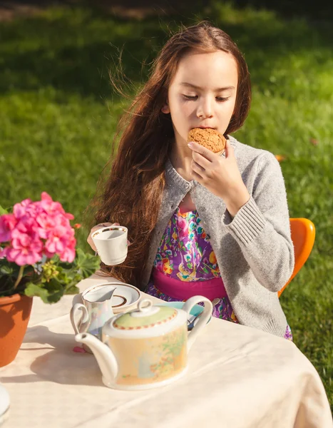 Beautiful girl having breakfast at yard and biting cookie — Stock Photo, Image