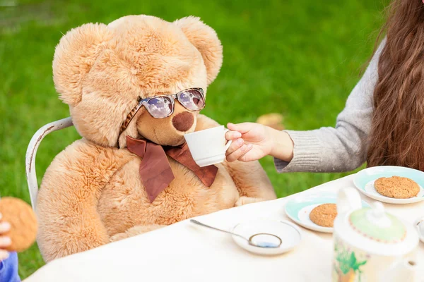 Oyuncak ayı bahçesinde çay veren kız — Stok fotoğraf