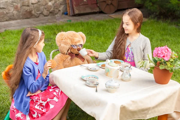 Girls having tea party with teddy bear at yard — Stock Photo, Image