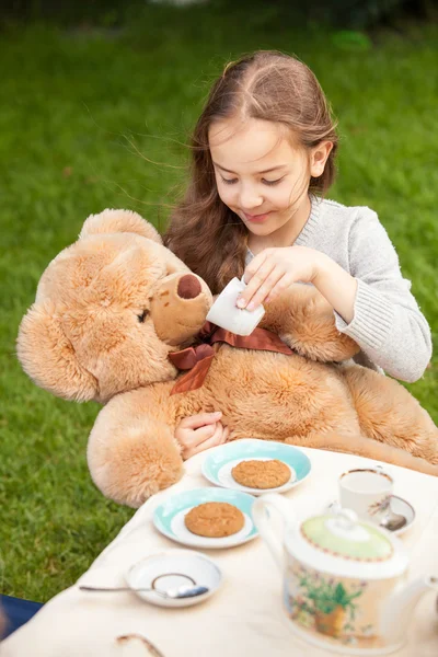 Peluş ayı için çay veren gülümseyen kız — Stok fotoğraf