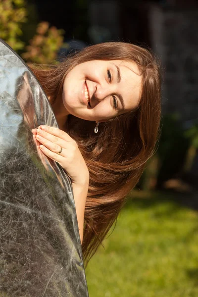 Portrait of smiling woman holding silver reflector — Stock Photo, Image