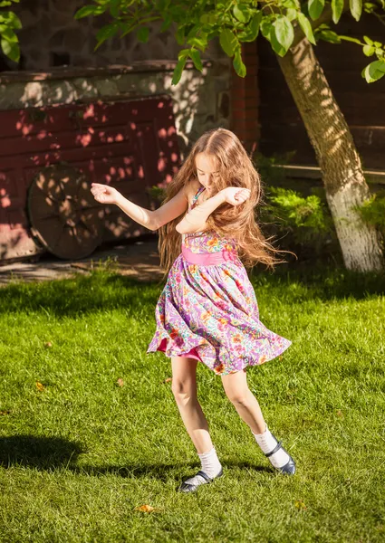 Mladá dívka tančí na trávě na slunečný den — Stock fotografie