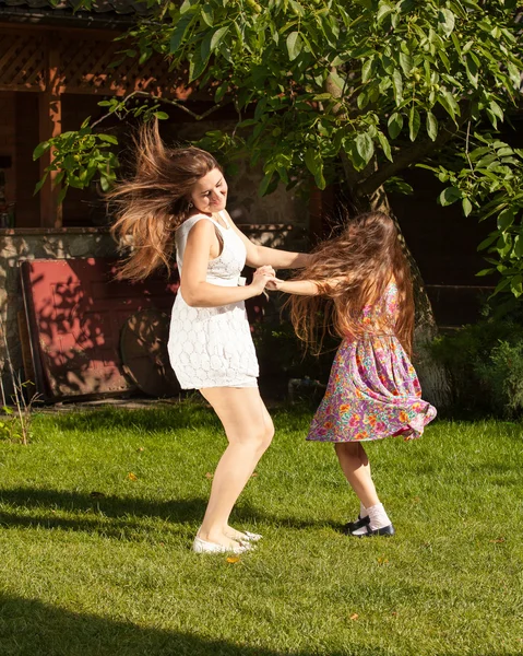 Мать и дочь танцуют на траве в солнечный день — стоковое фото
