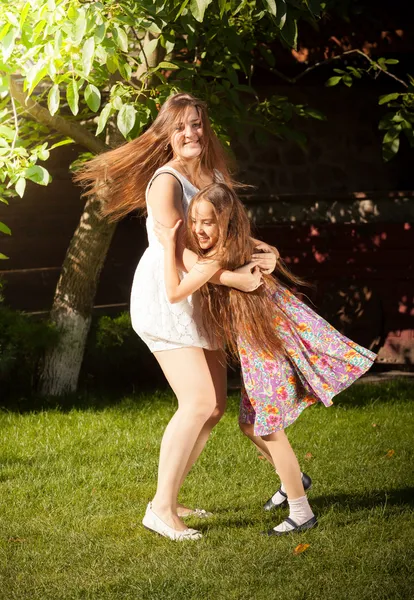 Jonge moeder en dochter dansen op gras op werf — Stockfoto