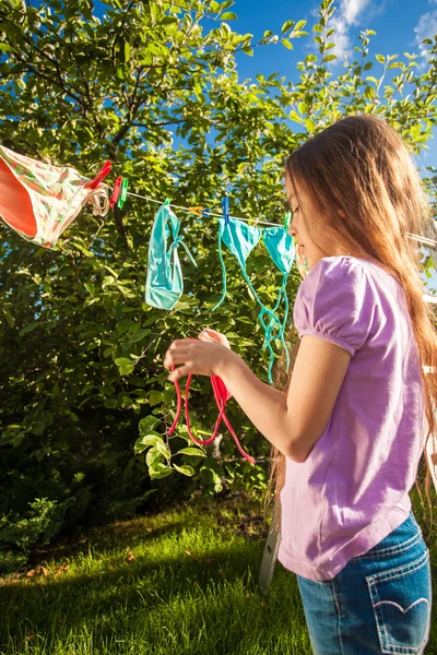 Photo de jeune fille séchant des vêtements sur corde à linge — Photo