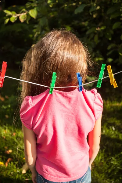 Girl being hanged by shirt on clothesline — Stock Photo, Image