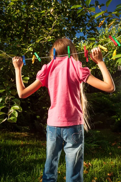 Giovane ragazza appesa sulla clothesline in giardino — Foto Stock