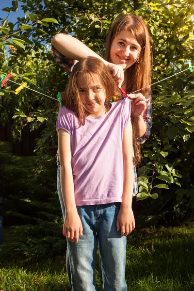 Woman hanging girl on clothesline at garden — Stock Photo, Image