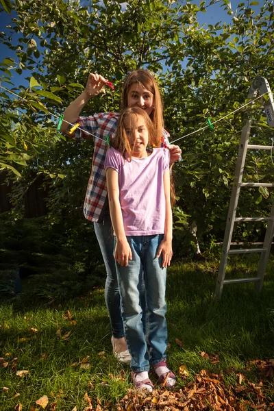 Mamma hängande dotter på strängen med klädnypa — Stockfoto
