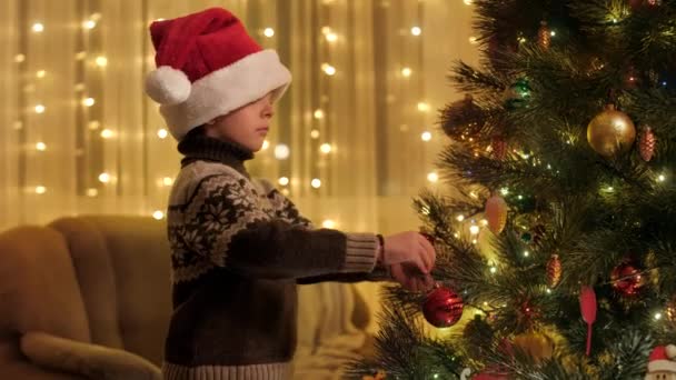 Szczęśliwy uśmiechnięty chłopiec dekorowanie choinki z czerwoną bombką. Czyste emocje rodzin i dzieci świętujących zimowe wakacje. — Wideo stockowe