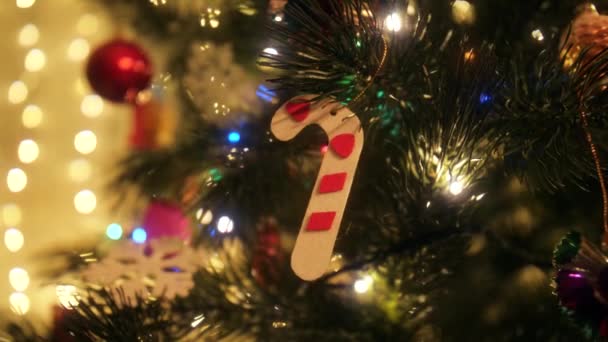 Χριστουγεννιάτικα στολίδια και μπιχλιμπίδια. Διακοσμητικό κερί καραμέλας κρέμεται σε χριστουγεννιάτικο δέντρο — Αρχείο Βίντεο