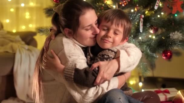 Mutlu anne ve oğul Noel arifesinde Noel ağacının altında oynayıp sarılıyor. Aileler ve çocuklar kış tatilini kutluyor. — Stok video