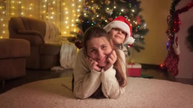 Mutlu bir çocuğun portresi. Annesi yerde yatıyor ve Noel ağacının yanında eğleniyor. Aileler ve çocuklar kış tatilini kutluyor.
