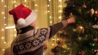 Gülümseyen anne ve küçük oğlu Noel ağacını oyuncaklar ve mücevherlerle süslüyorlar. Aile ve çocukların kış tatilini kutladıkları saf duygular..