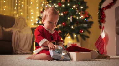 Mutlu gülümseyen çocuk Noel arifesinde oyun oynuyor ve hediye kutusunu açıyor. Aileler ve çocuklar kış tatilini kutluyor.