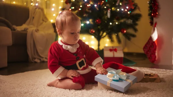 A kisfiú kinyitja a karácsonyi ajándékdobozt és belenéz. A téli ünnepeket ünneplő családok és gyermekek. — Stock Fotó