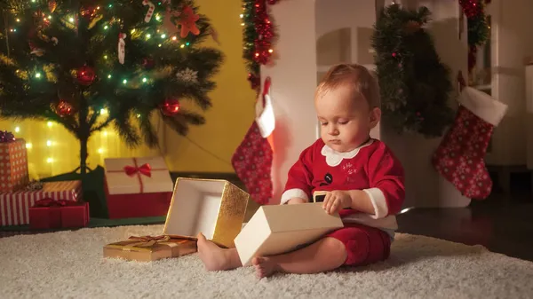 Menino brincando com caixa de presente de Natal e bugigangas decorativas coloridas. Famílias e crianças comemorando as férias de inverno. — Fotografia de Stock