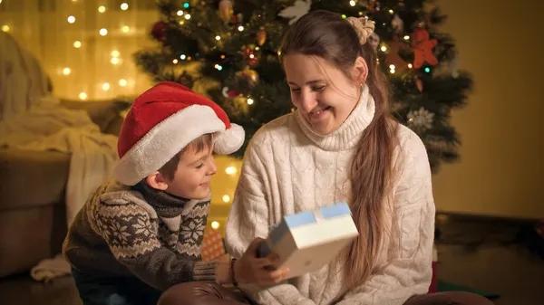 Söt pojke gör överraskning och ger julklapp rutan till sin mamma. Familjer och barn som firar vinterlov. — Stockfoto