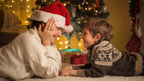 Garçon souriant palysant avec les mères chapeau de Père Noël la veille de Noël. Pures émotions des familles et des enfants qui célèbrent les vacances d'hiver. — Photo