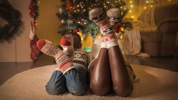 Gros plan de la famille en chaussettes de laine tricotées regardant l'arbre de Noël décoré à la maison. Pures émotions des familles et des enfants qui célèbrent les vacances d'hiver. — Photo