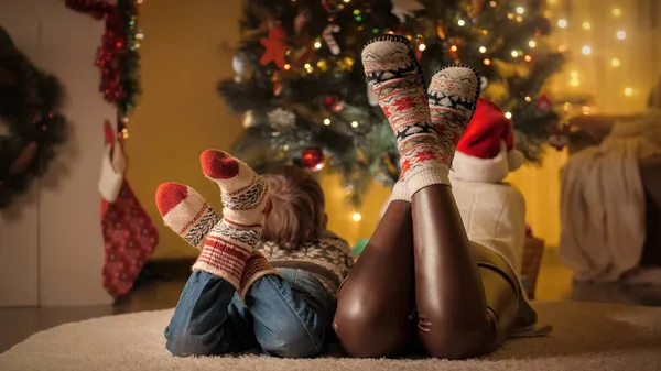 Szoros kép anya és fia kötött gyapjú zokni feküdt a padlón mellett karácsonyfa a házban — Stock Fotó