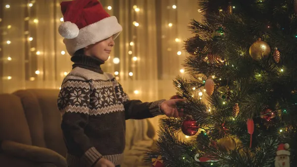 Glad leende pojke dekorera julgran med röd grannlåt. Rena känslor hos familjer och barn som firar vinterlov. — Stockfoto
