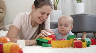 Annesi olan küçük bir çocuk oturma odasında halının üzerinde oyuncak oynuyor. Çocuk gelişimi, eğitim ve yaratıcılık kavramı