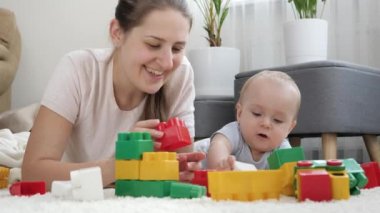 Halıda oğluyla oynayan ve tuğlalarla oyuncak kule yapan mutlu bir kadın. Çocuk gelişimi, eğitim ve yaratıcılık kavramı